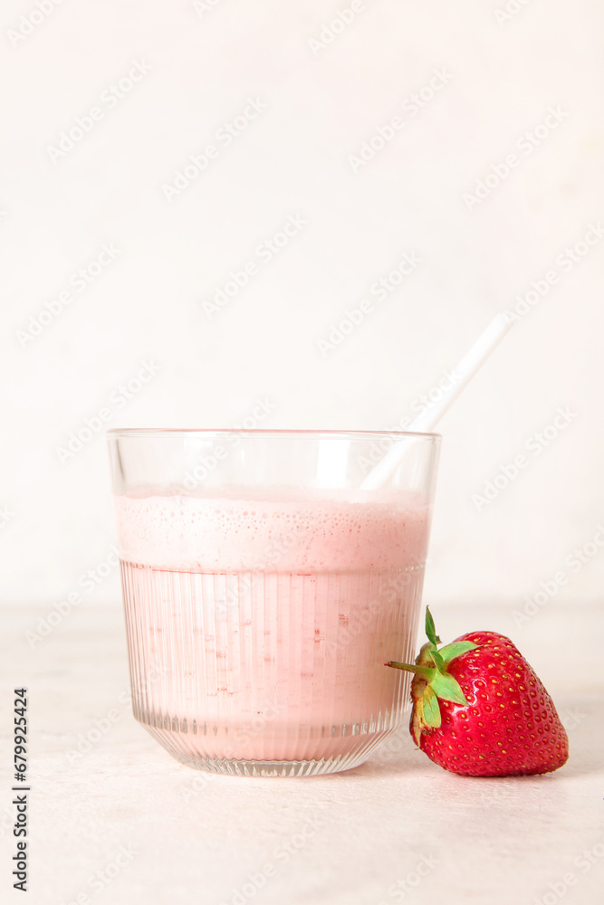 Glass of tasty strawberry smoothie on light background