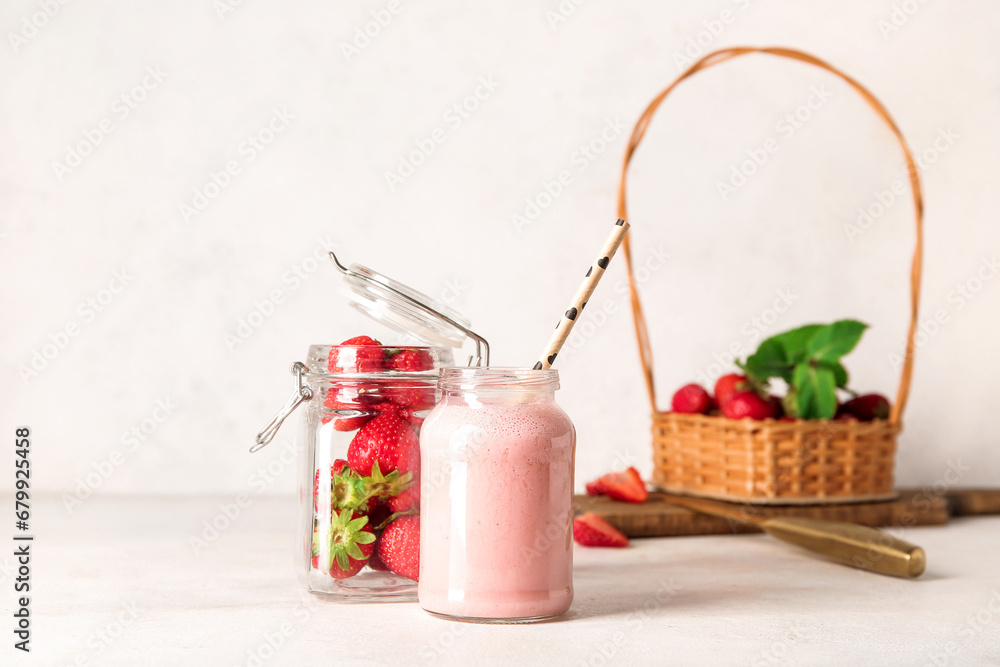 Mason jar of tasty strawberry smoothie on light background