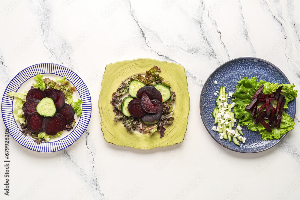 Plates with tasty vegetable salads on light background