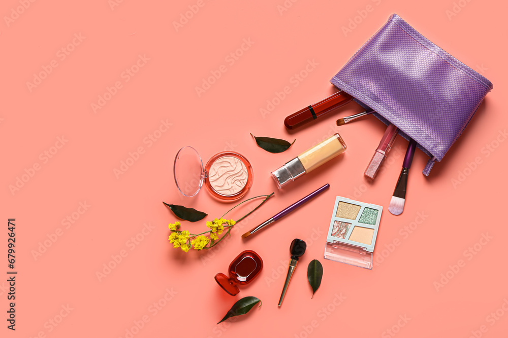 Stylish purple cosmetic bag with makeup products and beautiful flowers on coral background