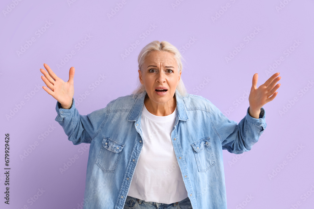 Upset mature woman on lilac background