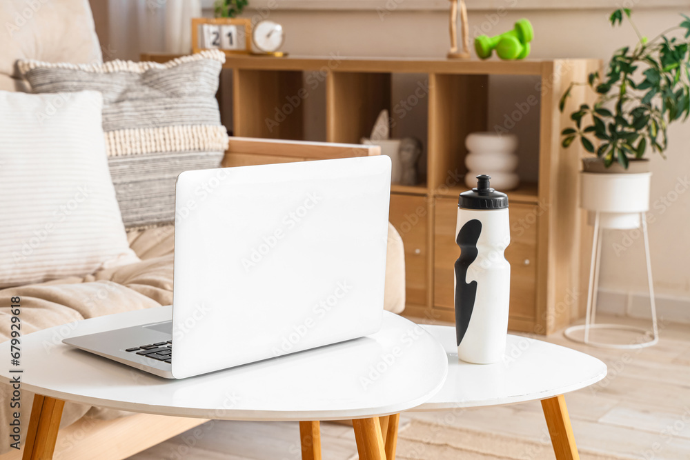 Laptop with sports water bottle on table in living room