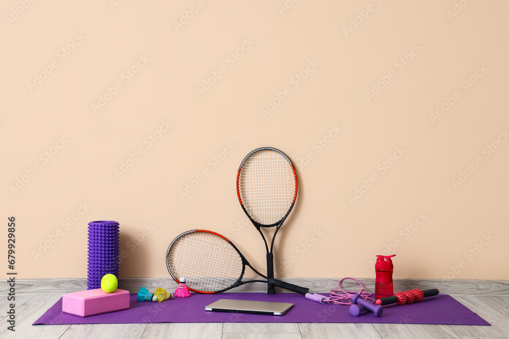 Sports equipment with laptop near beige wall in gym