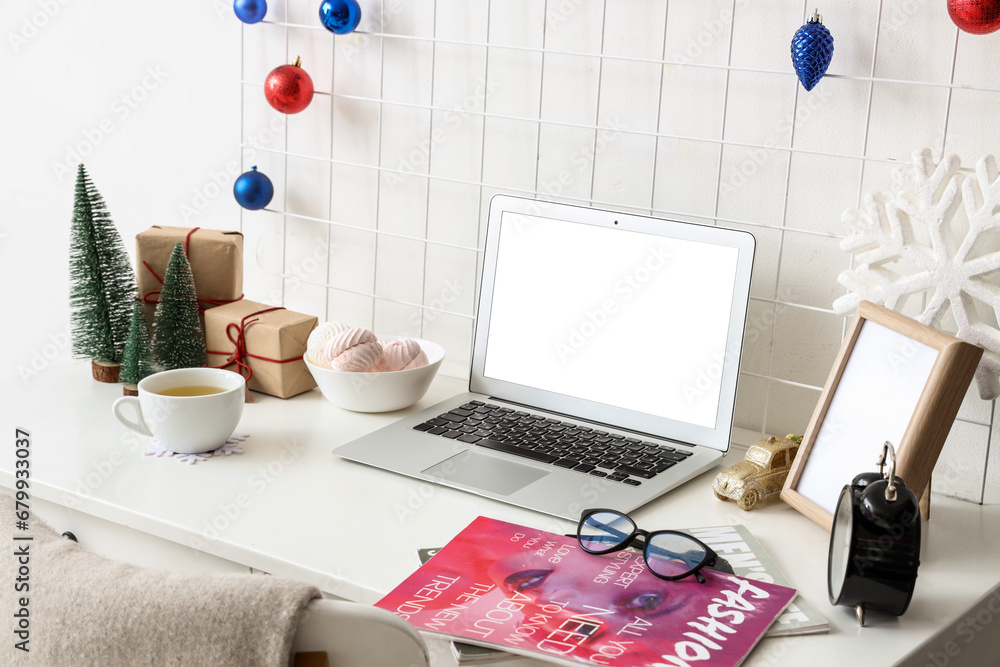 Workplace with blank laptop and Christmas decor in office