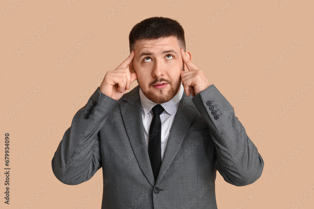 Young thoughtful businessman on beige background. Business idea concept