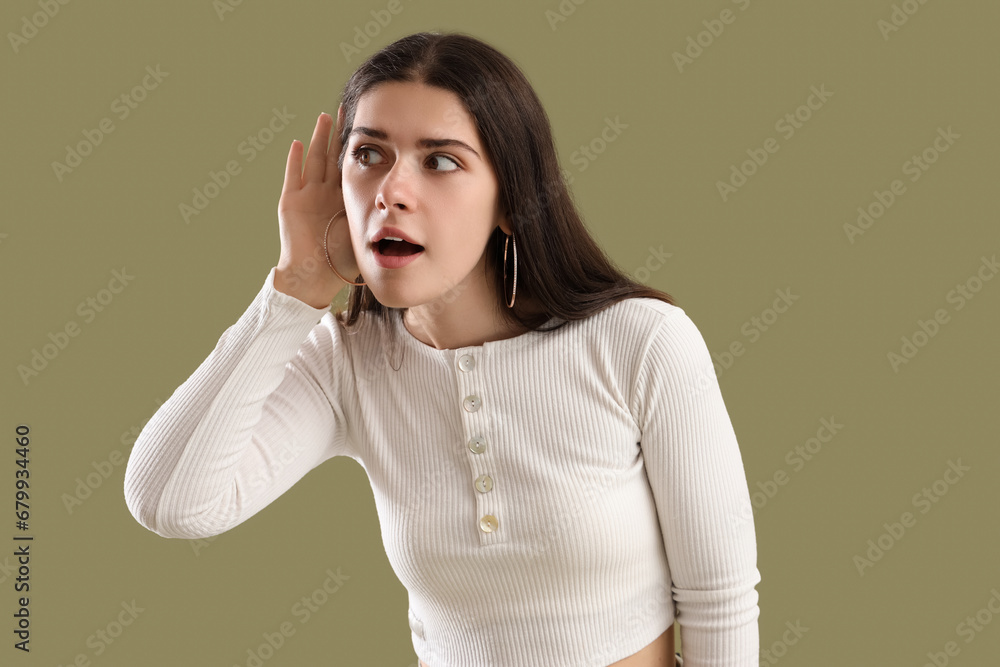 Young gossip woman trying to hear something on green background