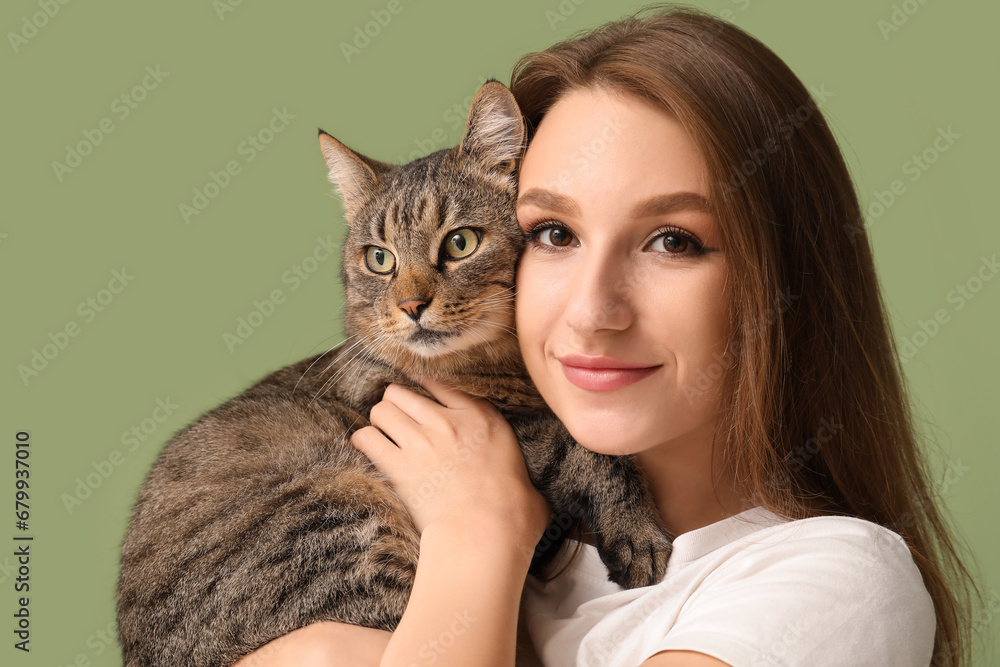 Pretty young woman with cute tabby cat on green background, closeup