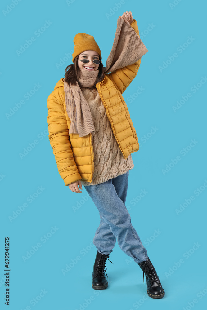 Young woman in winter clothes on blue background