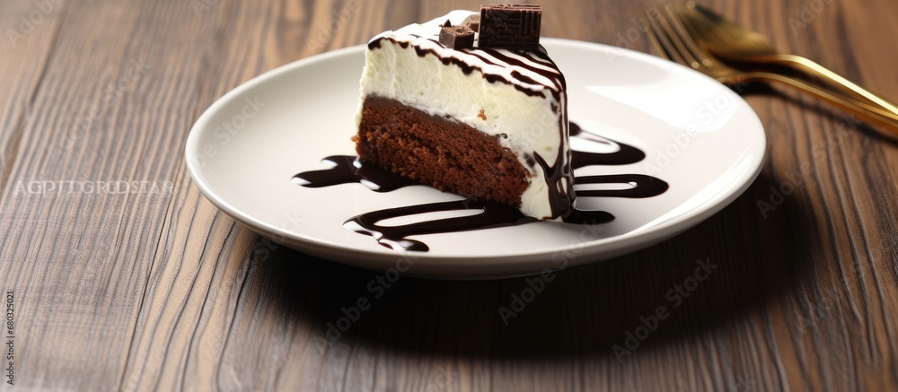 During the celebration, a delicious chocolate cake with a white and black design was placed on a wooden table as the background, enticing everyone with its mouthwatering appearance, proving that