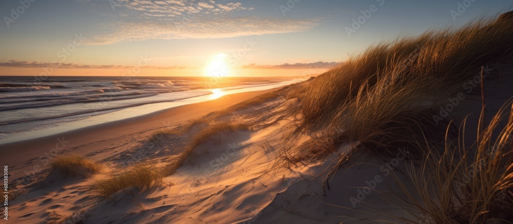 As the sun slowly sets over the mesmerizing landscape of Sylt, the crystal blue ocean waves gently kiss the sandy beach, creating a breathtaking summer scene for travelers seeking solace and