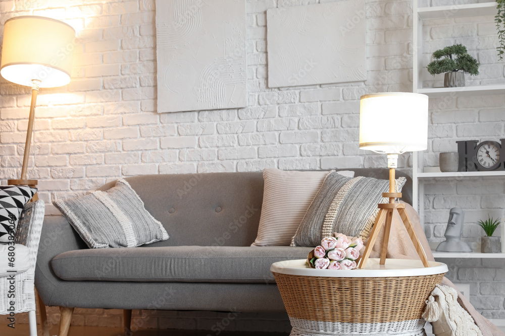 Interior of living room with cozy grey sofa and glowing lamps