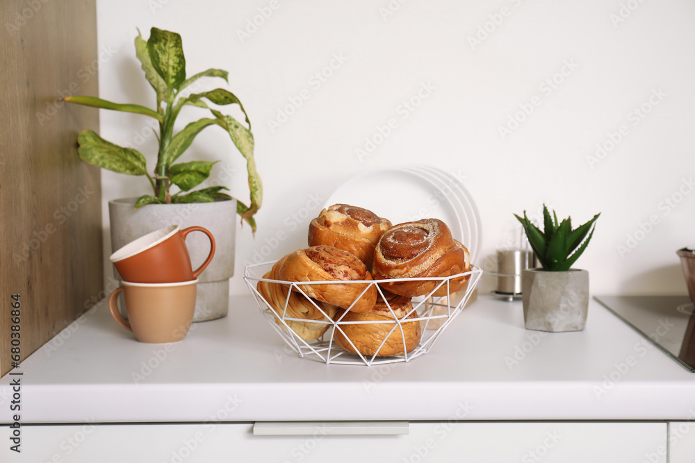 Basket with tasty cinnamon rolls on white kitchen counter