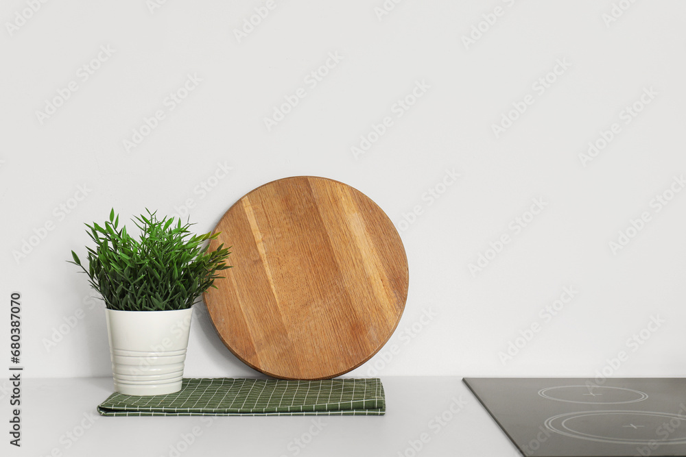 Wooden cutting board and green houseplant on white kitchen counter