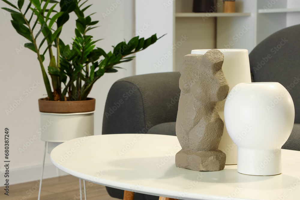 Decorative vase and figurine on coffee table in living room at evening, closeup