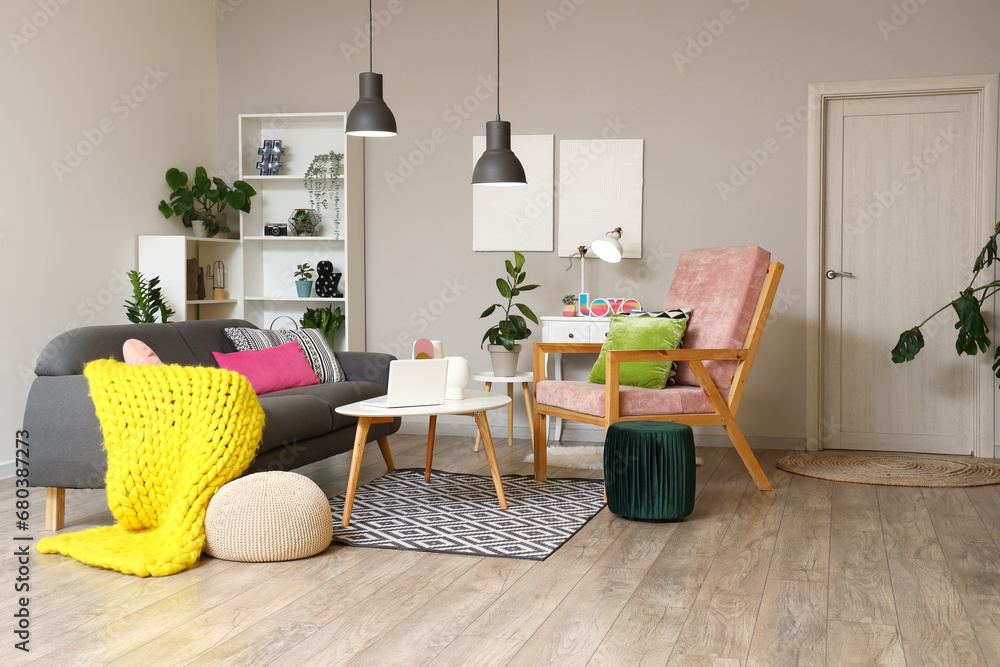 Interior of stylish living room with grey sofa, armchair and glowing lamps at evening