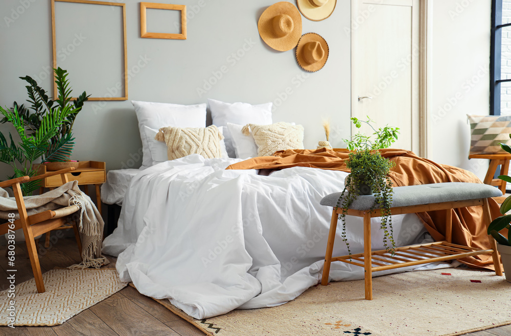 Interior of cozy bedroom with comfortable bed and grey bench