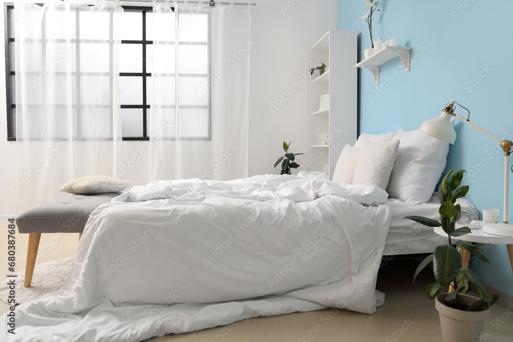 Interior of cozy bedroom with comfortable bed and grey bench