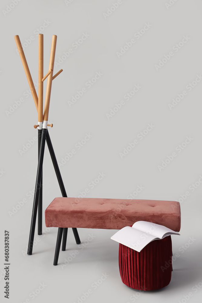 Pink bench and pouf with open book on grey background