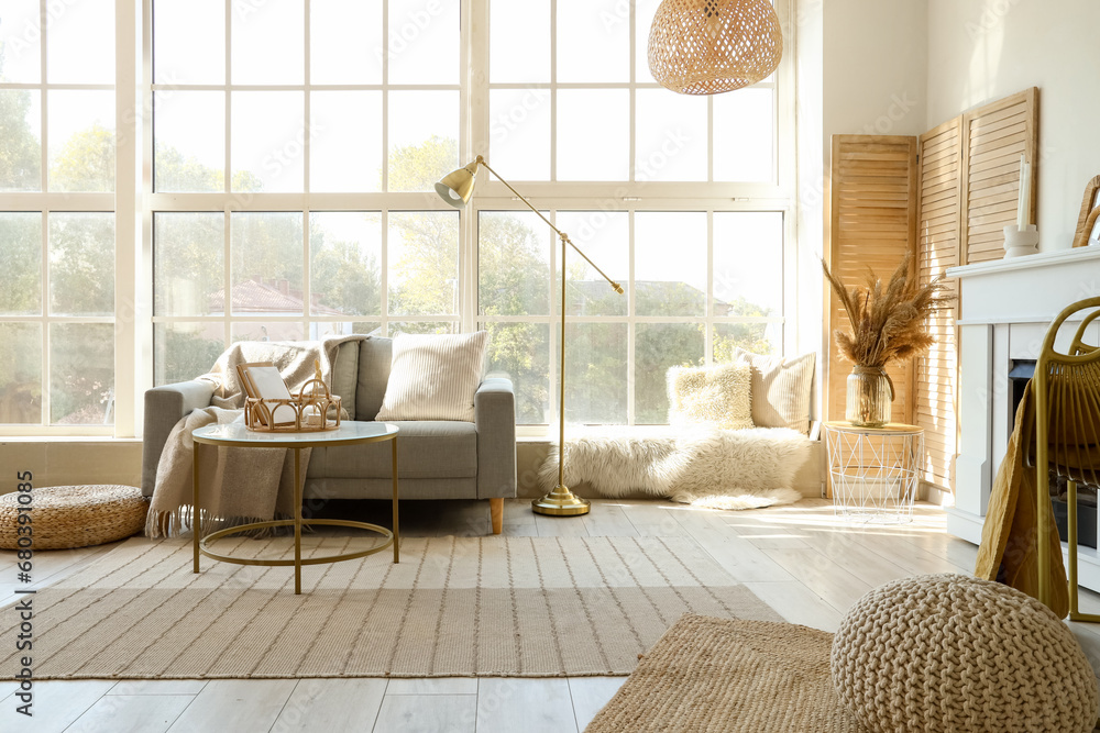 Interior of light living room with grey sofa, coffee table and fireplace