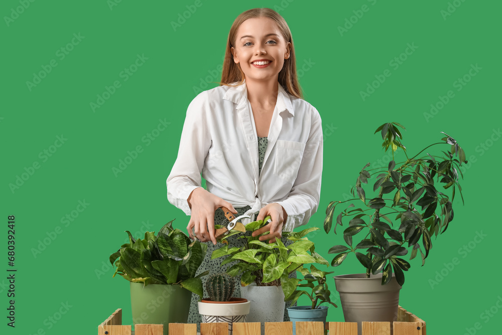 Female gardener at counter with plants on green background