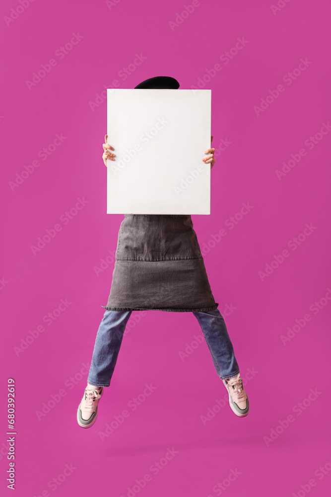 Jumping female artist with canvas on purple background