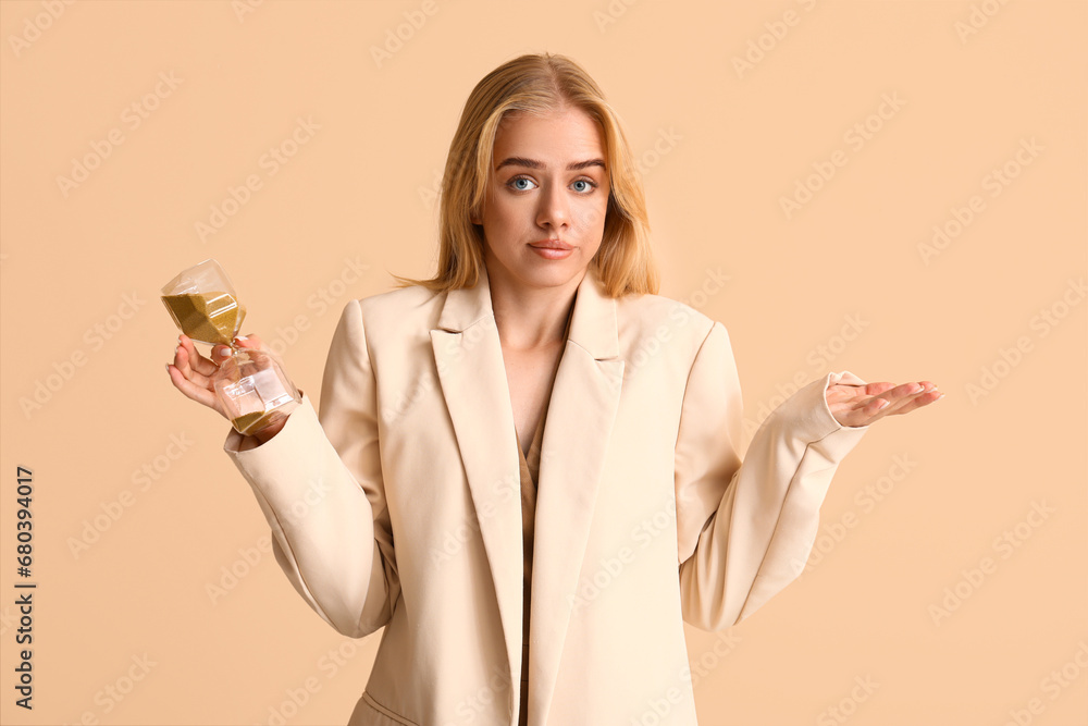 Young businesswoman with hourglass on beige background. Time management concept