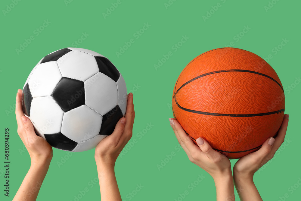 Female hands with basketball and soccer balls on green background