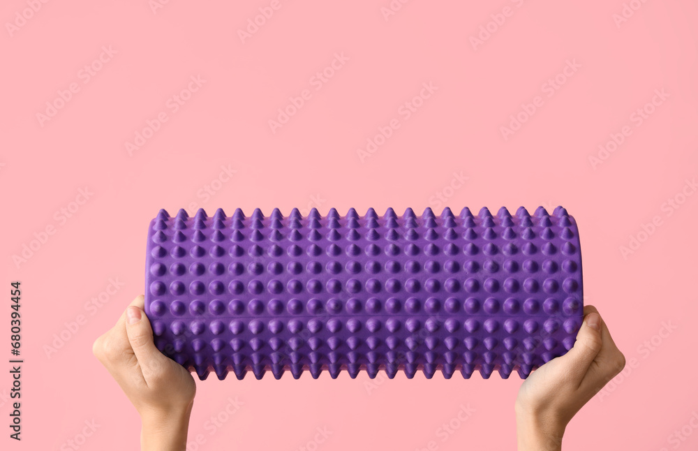 Female hands with foam roller on pink background