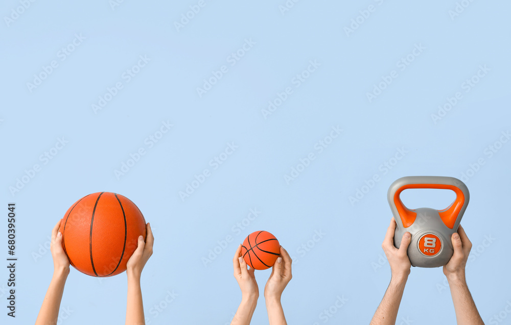 Female hands with balls for playing basketball and kettlebell on blue background