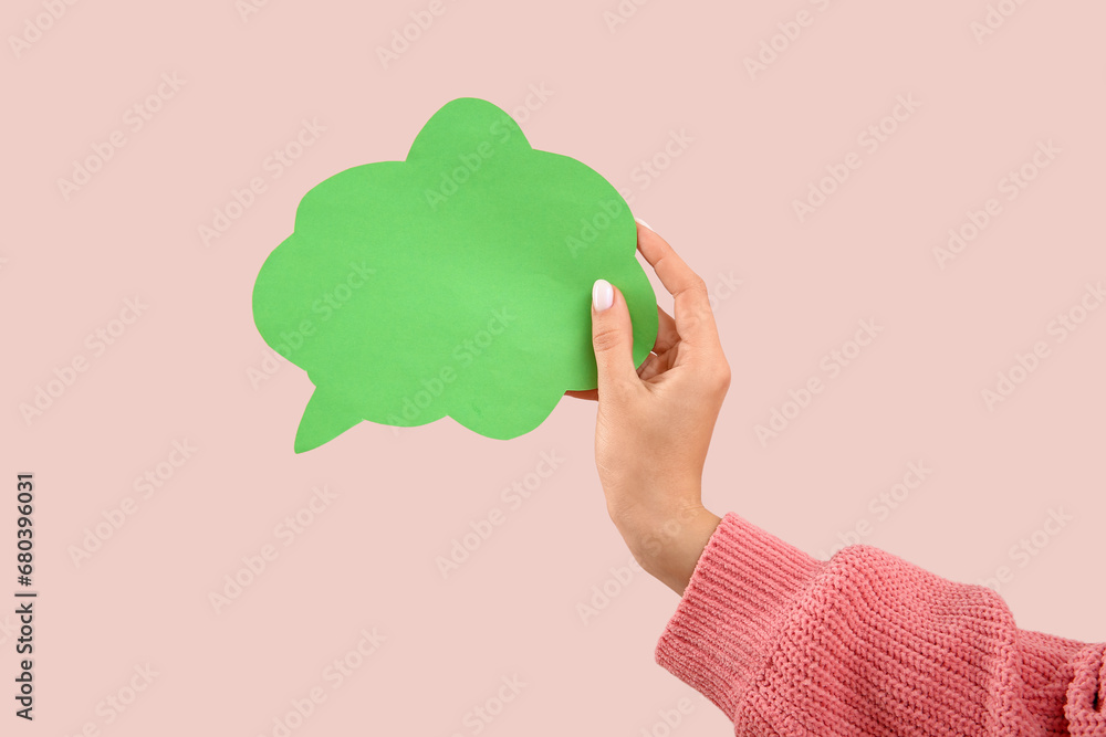 Female hand with blank speech bubble on pink background