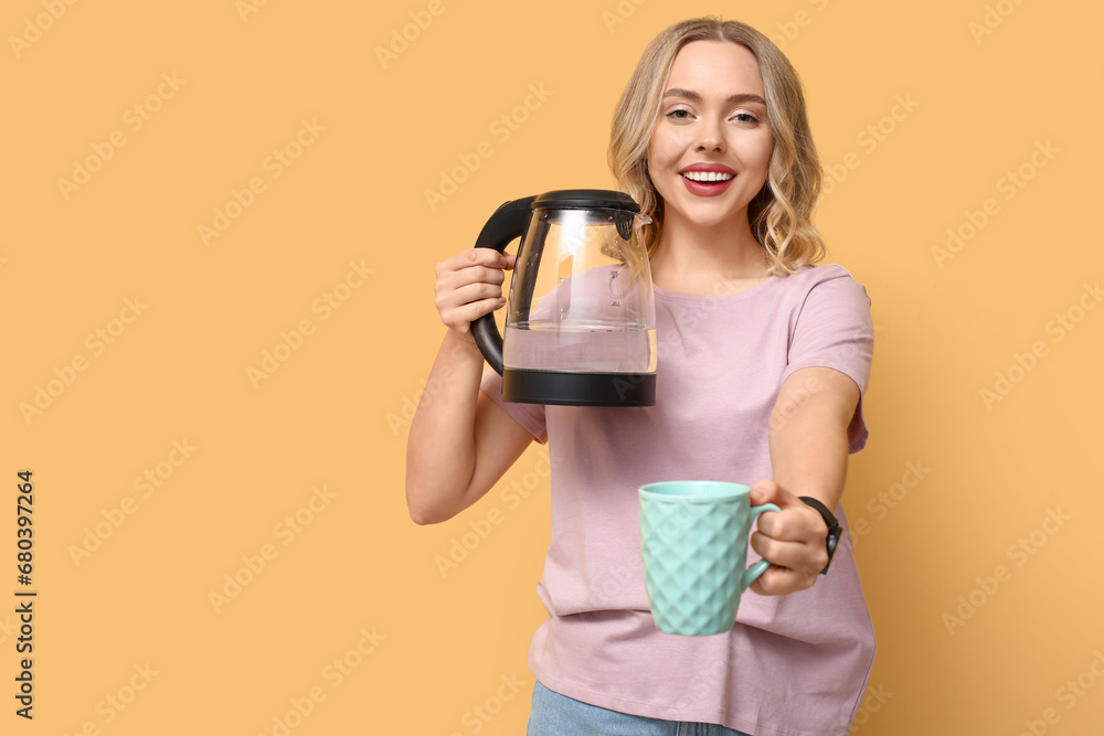 Beautiful young woman with modern electric kettle and cup on yellow background