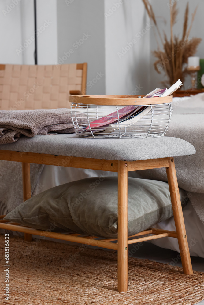 Bedside bench with pillow, blanket and magazines in bedroom