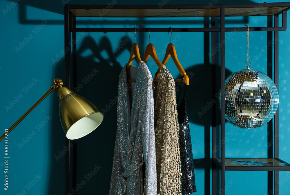 Shelving unit with clothes and disco ball near blue wall in room