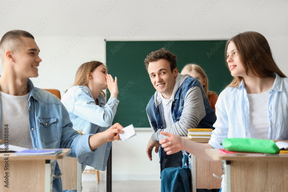 Students sitting and gossiping with his classmates in classroom