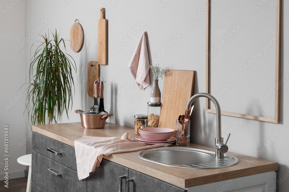 Grey counters with cutting boards, sink, utensils and cooking pot in kitchen