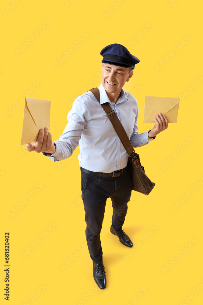 Mature postman with envelopes on yellow background