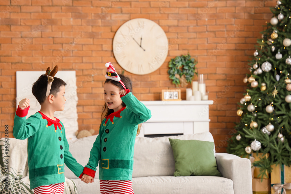 Adorable little children in elfs costumes on Christmas eve at home