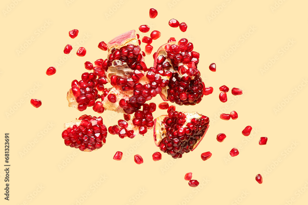 Flying fresh pomegranates with seeds on yellow background