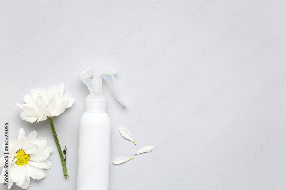 Composition with bottle of cosmetic product and beautiful chamomile flowers on light background