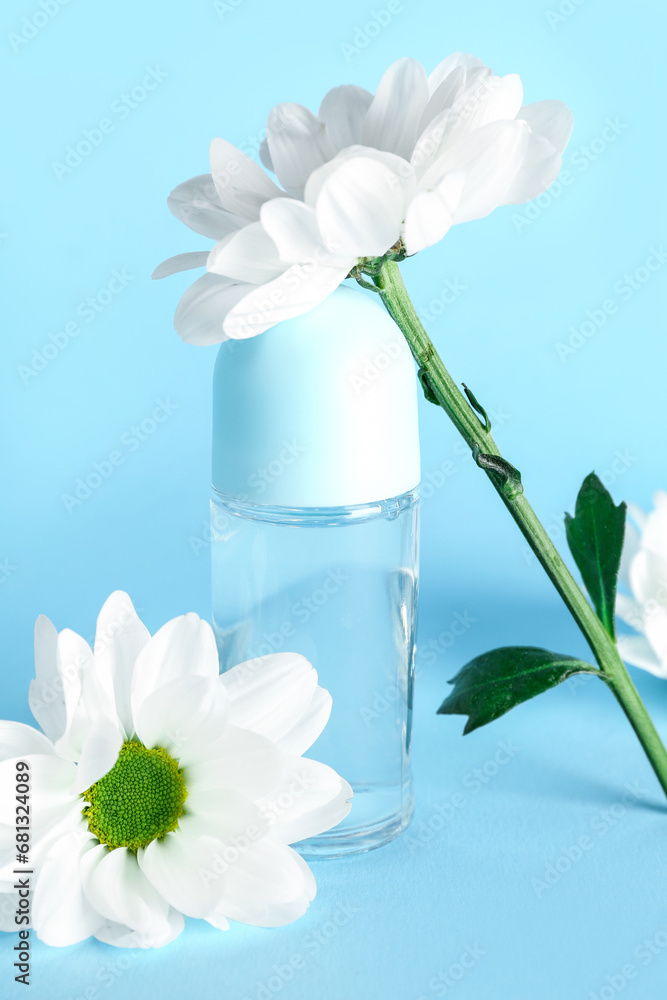 Bottle of deodorant with chamomile flowers on color background