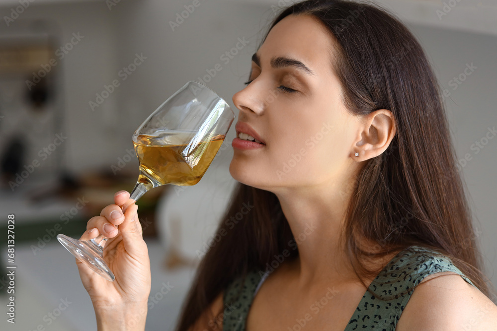 Young woman with glass of wine in kitchen, closeup