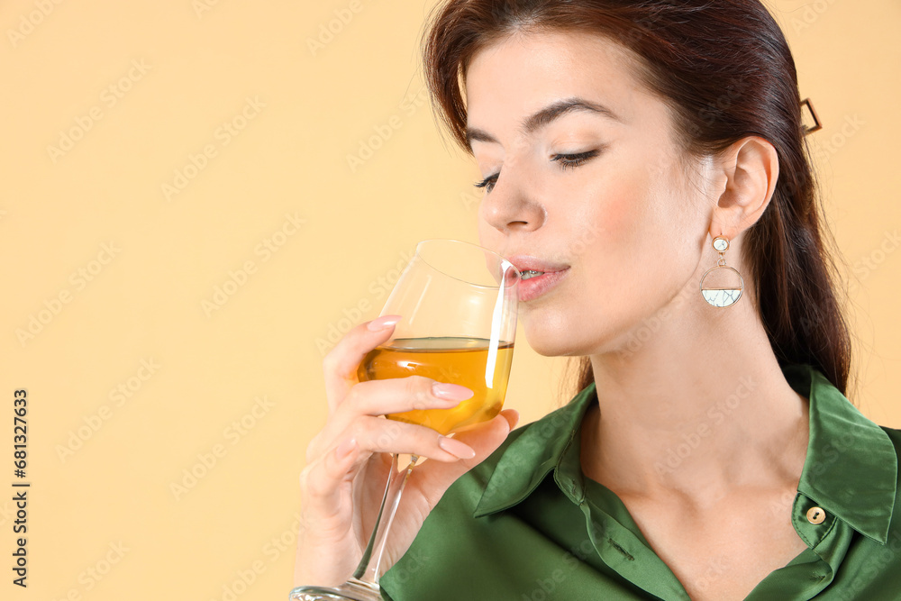 Beautiful young woman with glass of wine on beige background, closeup