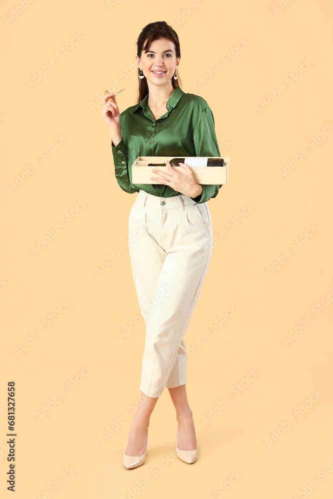 Beautiful young woman with glass of wine on beige background