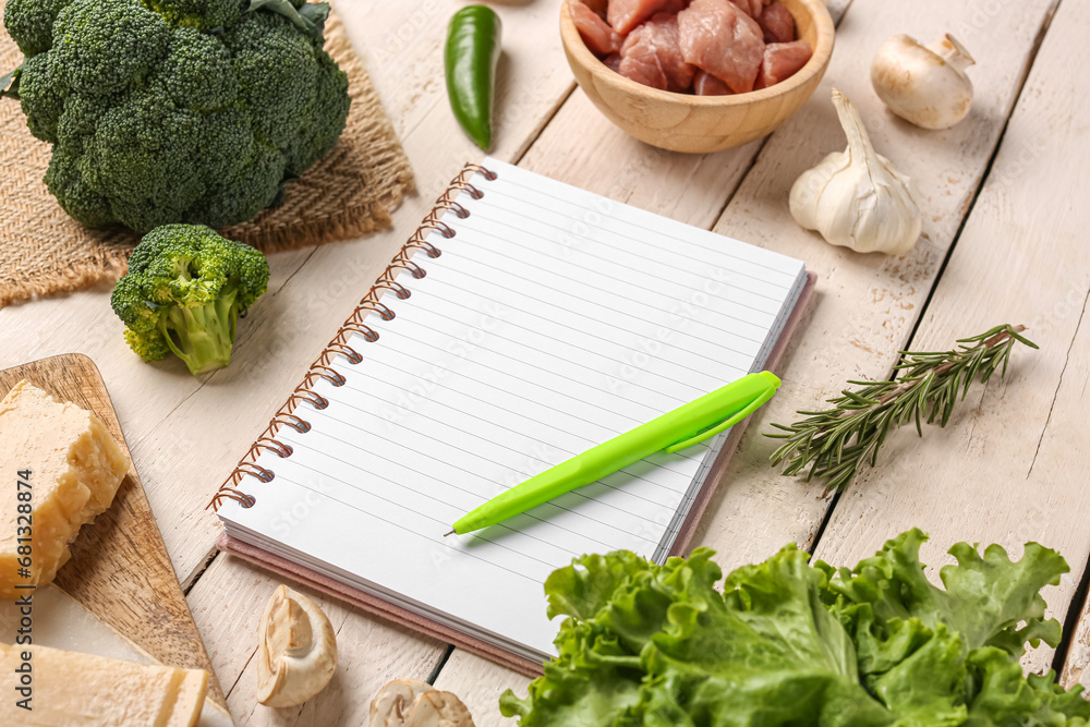 Blank notebook with fresh vegetables on white wooden table