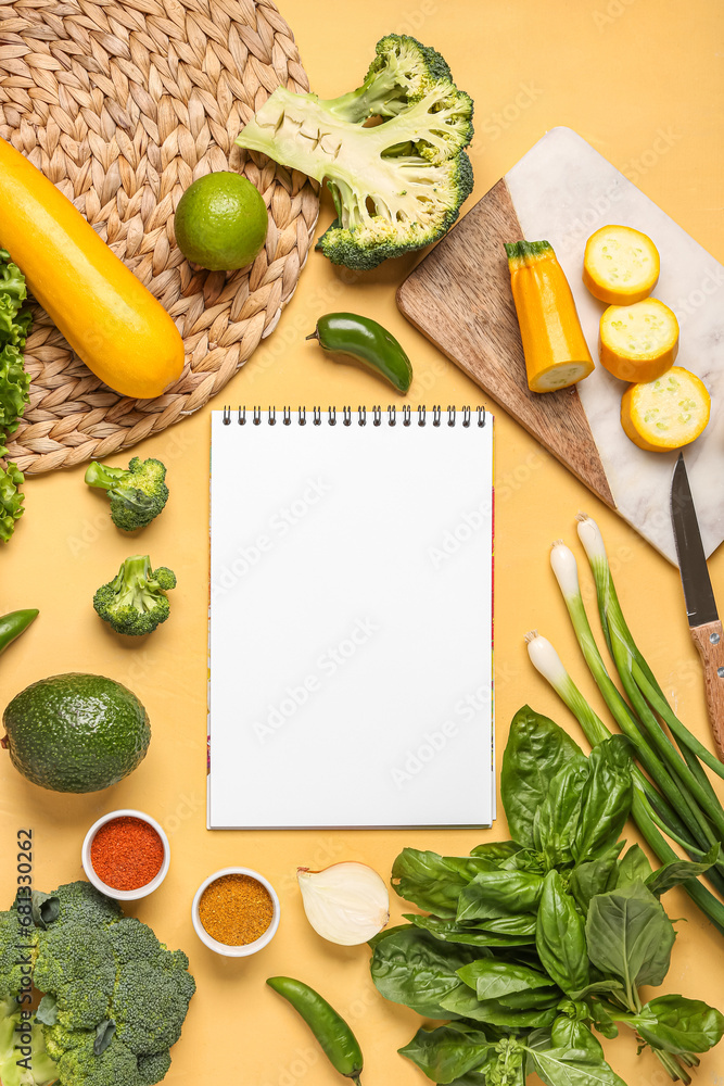 Composition with blank recipe book, fresh vegetables and spices on yellow background