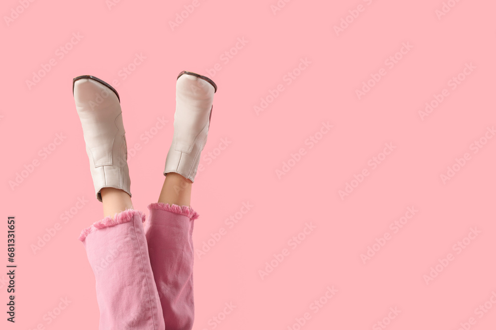 Legs of young woman in stylish beige leather boots on pink background