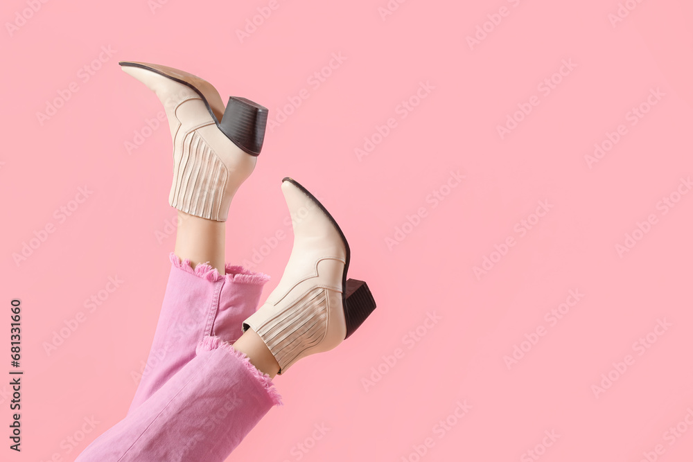 Legs of young woman in stylish beige leather boots on pink background