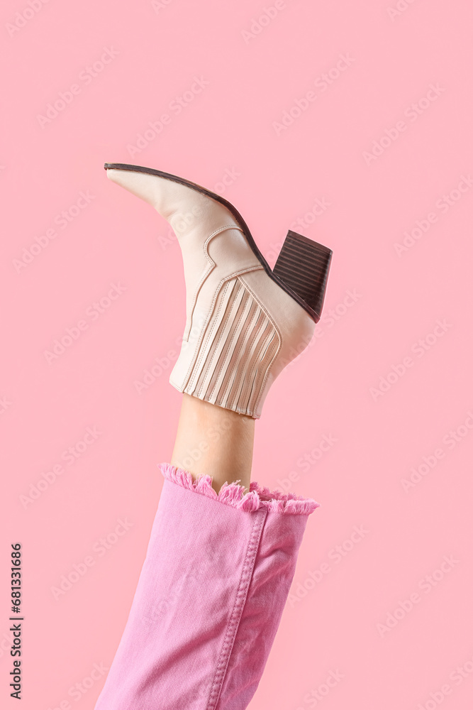 Leg of young woman in stylish beige leather boot on pink background