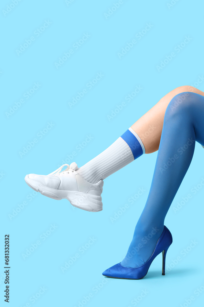 Legs of young woman in different stylish shoes on blue background