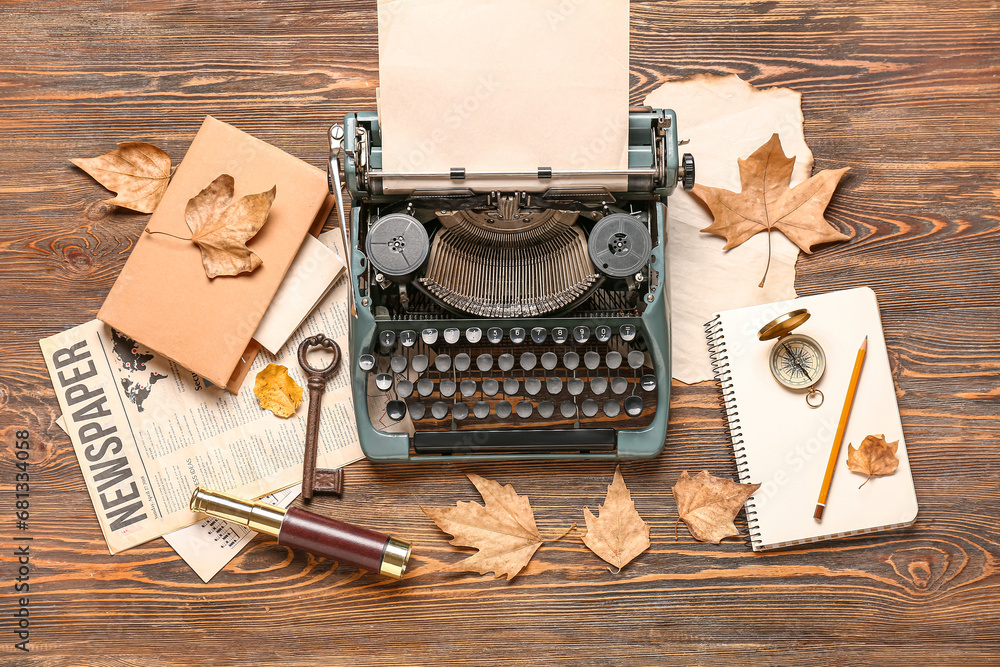 Vintage typewriter, compass, spyglass, book, notebook, newspaper and autumn leaves on wooden background